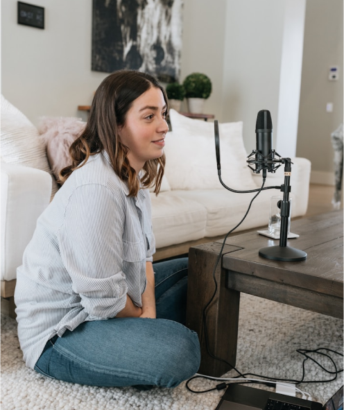 Woman sitting on the floor with a microphone and laptop